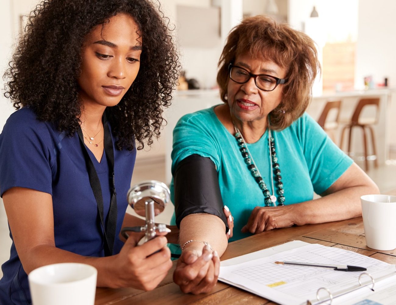 Female healthcare worker checking the blood pressure of a senior woman during a home visit